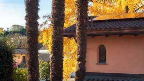 A building with a tiled roof, a window with a decorative frame, and a tree with yellow leaves. - Near the lake and the center (FLORIDA ASCONA Room 15) (Ascona)