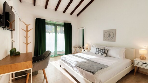 A bedroom with a bed, a desk, a chair, a TV, a window with curtains, and a wall art piece. - Near the lake and the center (FLORIDA ASCONA Room 15) (Ascona)