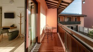A balcony with a wooden railing, a table with chairs, and a television on the wall. - Near the lake and the center (FLORIDA ASCONA Room 15) (Ascona)
