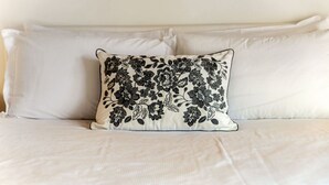 A bed with white bedding and a single decorative pillow with black floral patterns. - Near the lake and the center (FLORIDA ASCONA Room 19) (Ascona)