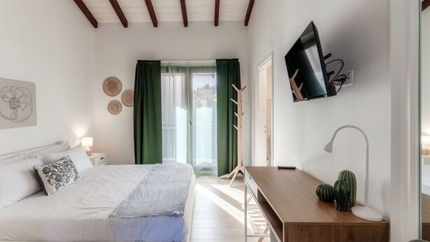 A bedroom with a bed, a desk, a TV, and a window with curtains. - Near the lake and the center (FLORIDA ASCONA Room 19) (Ascona)