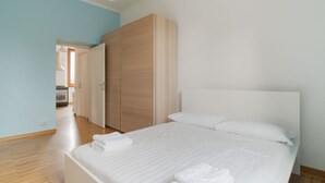 A bedroom with a bed, a wardrobe, and a view into another room. - GuestHost - Comfortable and bright 70m2 apartment, for 4 people, located on the 3rd floor of a building with elevator (NOT SUITABLE FOR DISABLED GUESTS). The property is located in the Isola neighborhood, very young and full of services, well served by p (Milan)