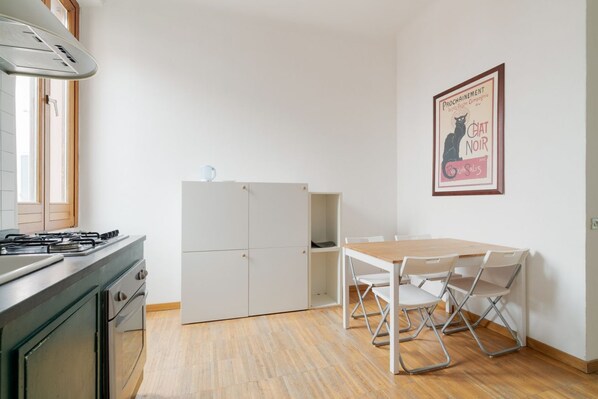 Una cocina con estufa, alacenas y una mesa de comedor con sillas.