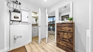 A modern kitchen with white cabinets, a wooden cabinet, and a view into the dining area. - Modern 4BR London Home with Games Room Large Garden Free Parking and Fast WiFi (Wembley)