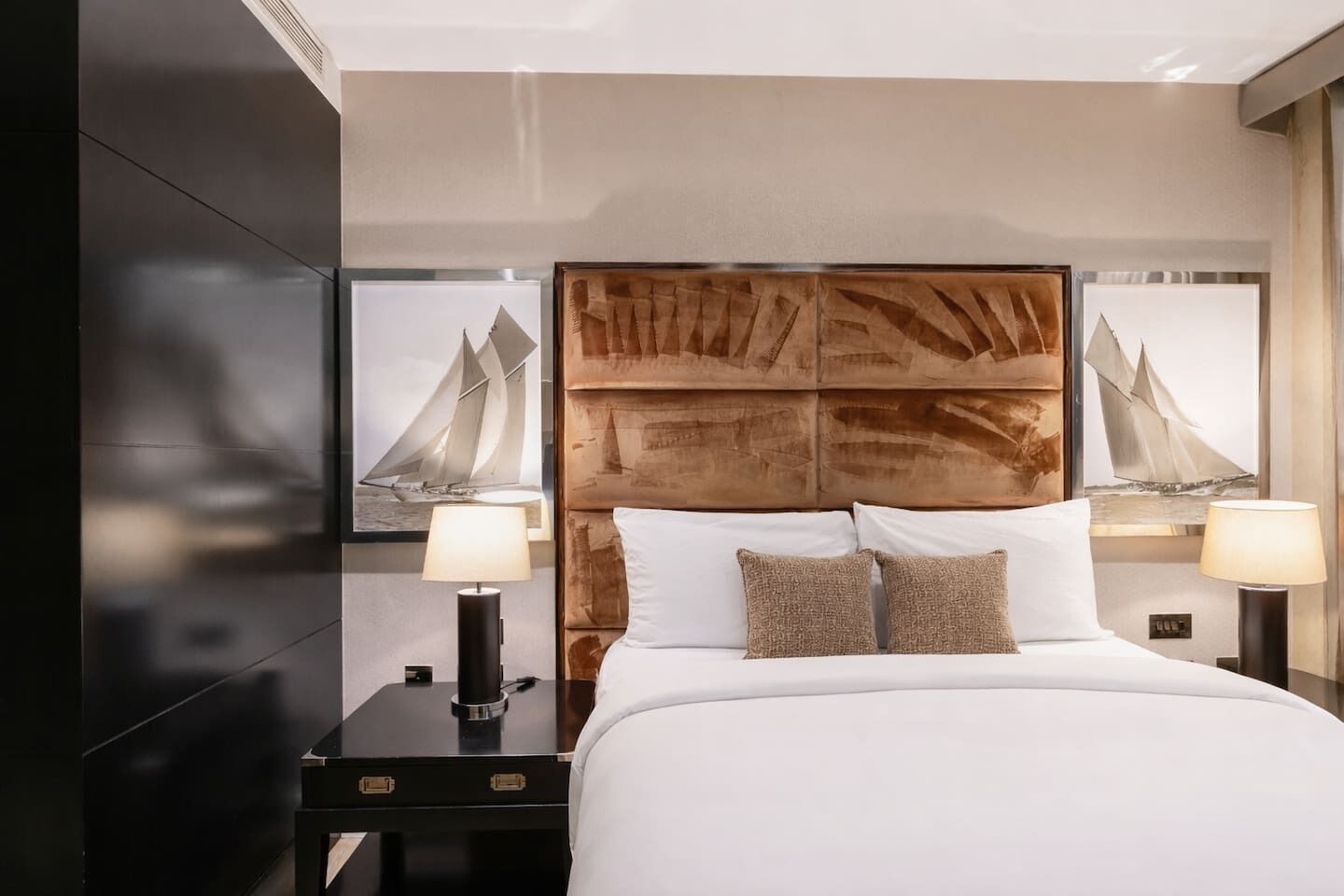 A hotel room with a large bed, two bedside tables, and a headboard with a textured design.