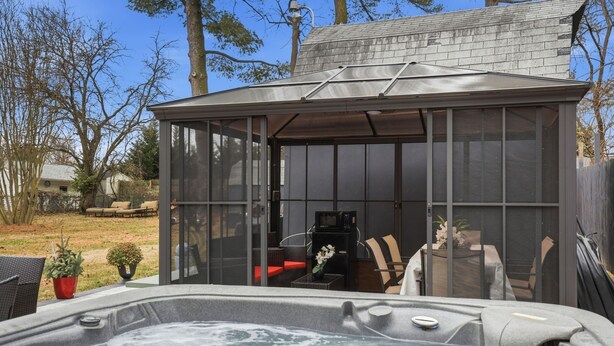 A hot tub with a covered seating area, surrounded by a fenced yard with outdoor furniture. - Suite Retreat (Severn)