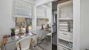 A room with a desk, chair, potted plants, a lamp, and a walk-in closet with shelves and hanging space. - Suite Retreat (Severn)