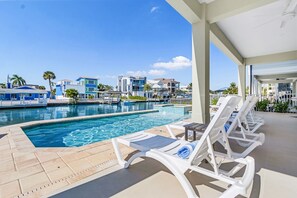 Un espace aménagé au bord de la piscine, avec des chaises longues et une vue sur un quartier résidentiel.