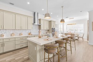 Une cuisine moderne dotée d’un îlot central, de tabourets de bar et de luminaires suspendus.