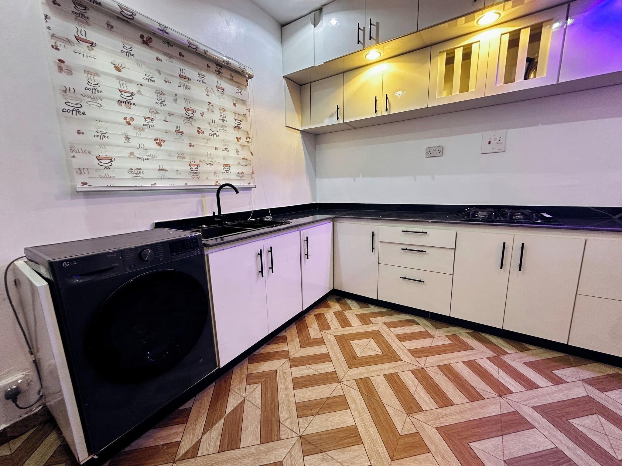 Una cocina compacta con lavadora, pileta y un respingo decorado.