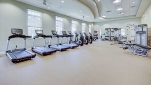 Une salle de sport équipée de tapis de course, de vélos elliptiques et de matériel de musculation.