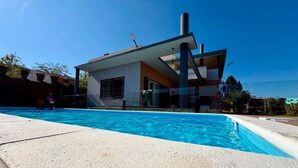 A modern house with a swimming pool, a garage, and a clear blue sky.
