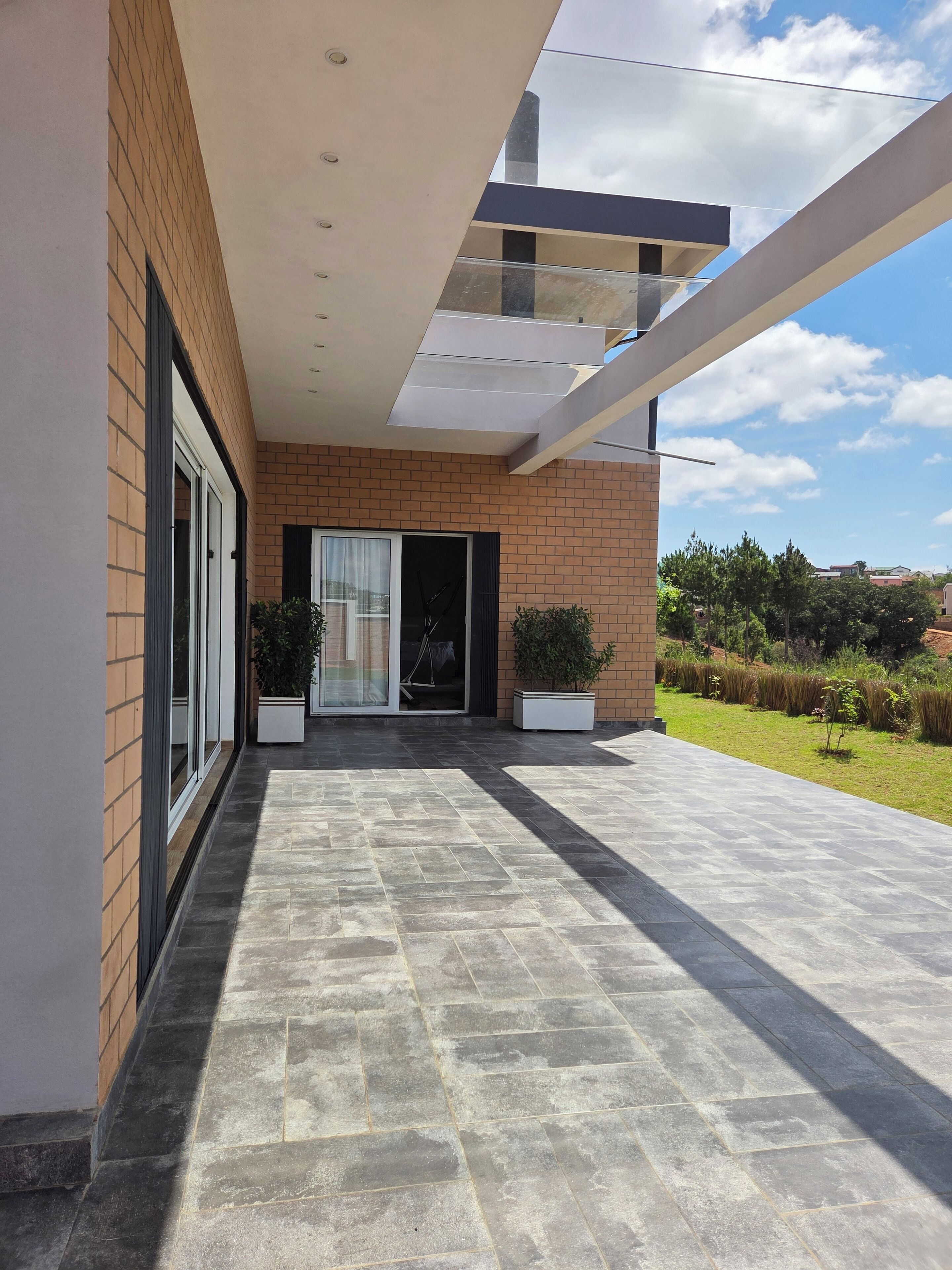 Un bâtiment moderne doté d’un toit plat, de grandes fenêtres et d’une terrasse dallée.