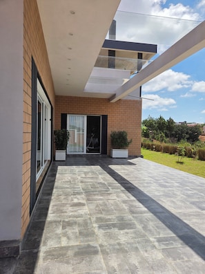A modern building with a flat roof, large windows, and a paved patio area.