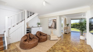 A spacious living area with a staircase, a dining area, and a view of the outdoors. - Absolute Birubi Beachfront - Luxury Pet Friendly (Anna Bay)