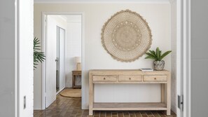 Un pasillo con una consola de madera, un tapiz tejido y una planta en maceta.