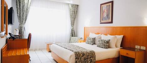 Una habitación de hotel con una cama grande, un escritorio y una silla.