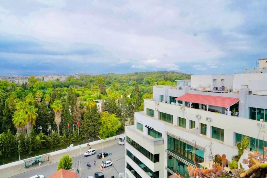 Un edificio moderno con varios pisos, amplias ventanas y un tejado rojo.