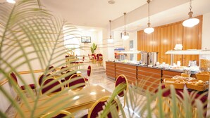 Ein moderner Essbereich mit einem Buffet, das verschiedene Speisen und Getränke umfasst, sowie eine Sitzordnung mit Tischen und Stühlen.