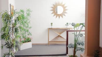 A staircase with a wooden railing, a decorative sunburst mirror on the wall, and potted plants on either side.