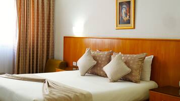 A neatly made bed with a wooden headboard, a bedside table, and a framed picture on the wall.