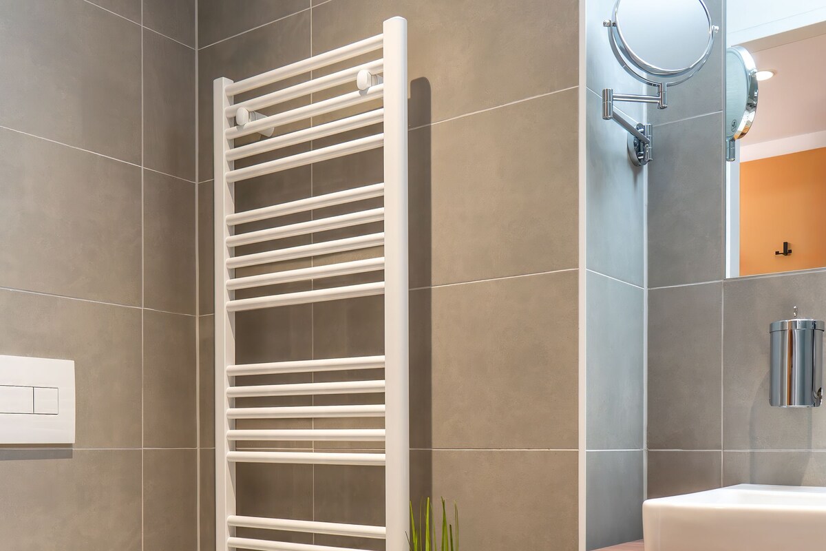 A modern bathroom with a white toilet, a towel rack, and a sink with a mirror.