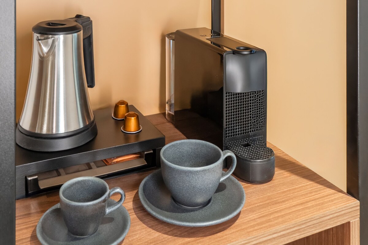 Una cocina moderna con cafetera, dos tazas, hervidor y una figurita decorativa de un ciervo en un estante.