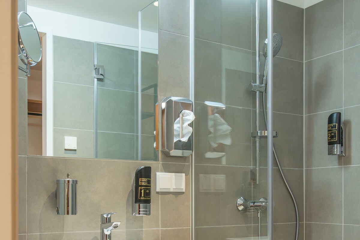 A modern bathroom with a glass shower enclosure, a sink with a wooden countertop, and a mirror.