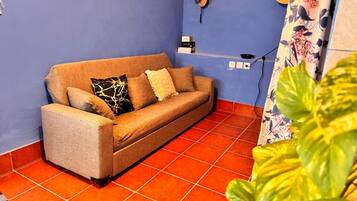 Una habitación con sofá, toma corriente e enchufe.