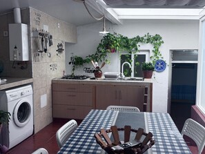 Una cocina compacta con estufa a gas, lavamanos y lavadora.