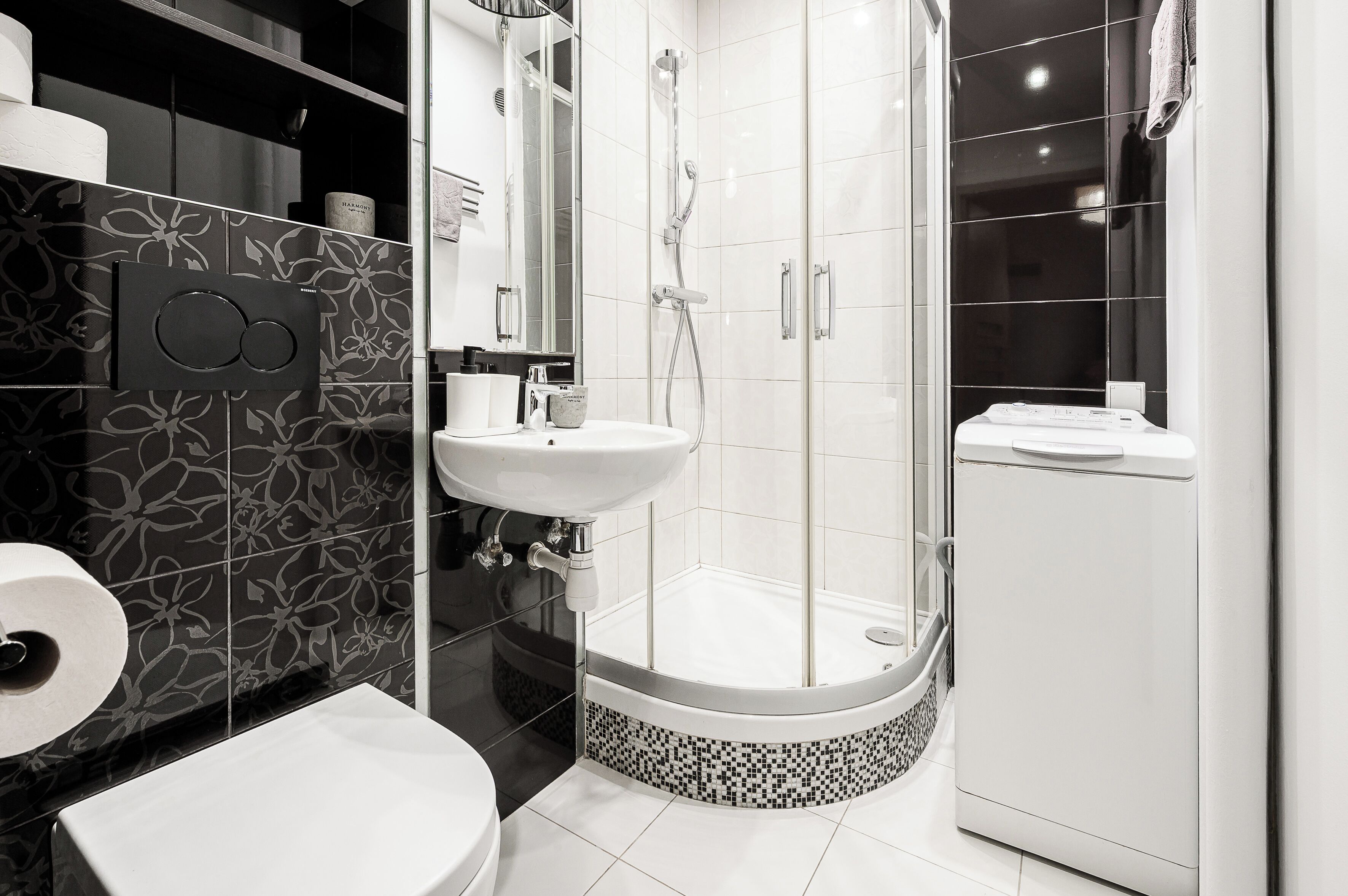 Un baño moderno con ducha de vidrio, lavamanos blanco y retrete.