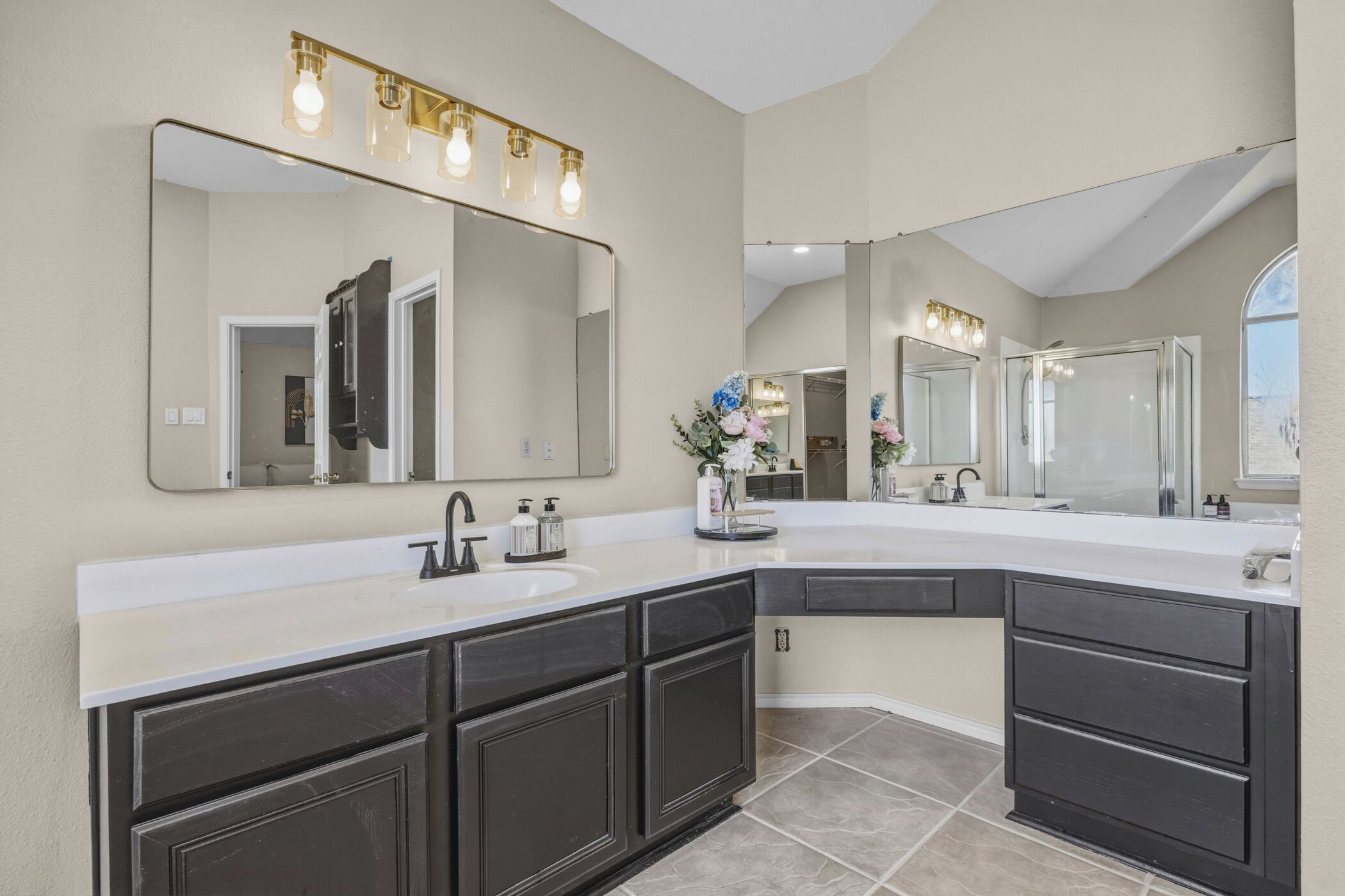 A modern bathroom with a large vanity, double sinks, and a large mirror with lights.
