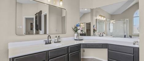 A modern bathroom with a large vanity, double sinks, and a large mirror with lights.