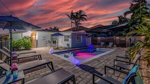 Un jardin avec une piscine, du mobilier de jardin et un petit bâtiment sur lequel est apposée une enseigne.