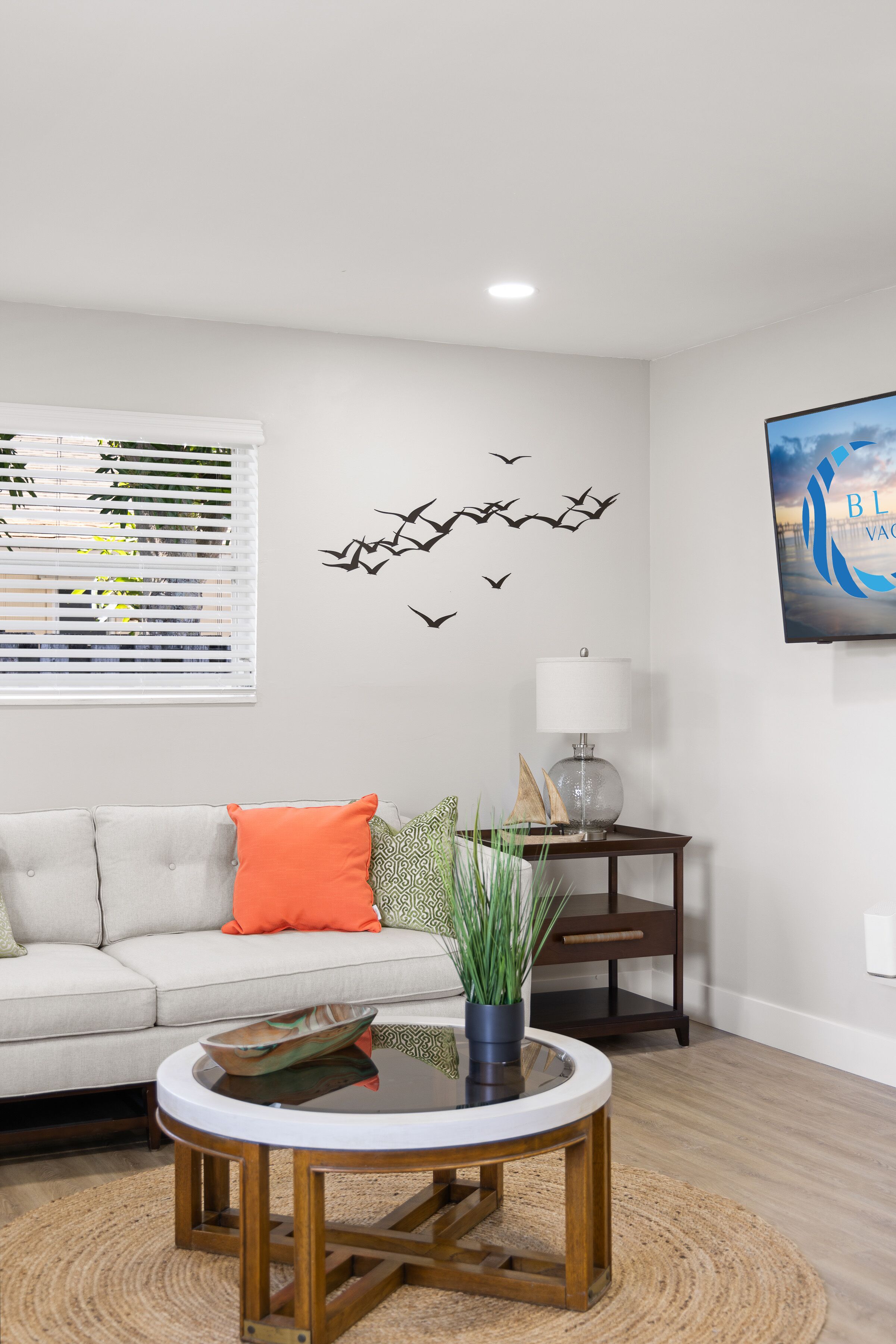 A living room with a sofa, a coffee table, a lamp, and wall decorations.