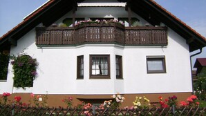 A two-story building with a balcony, windows, and a fence with flowers. - Apartment 'Eva Maria' with Shared Pool, Garden and Wi-Fi (Mahlberg)