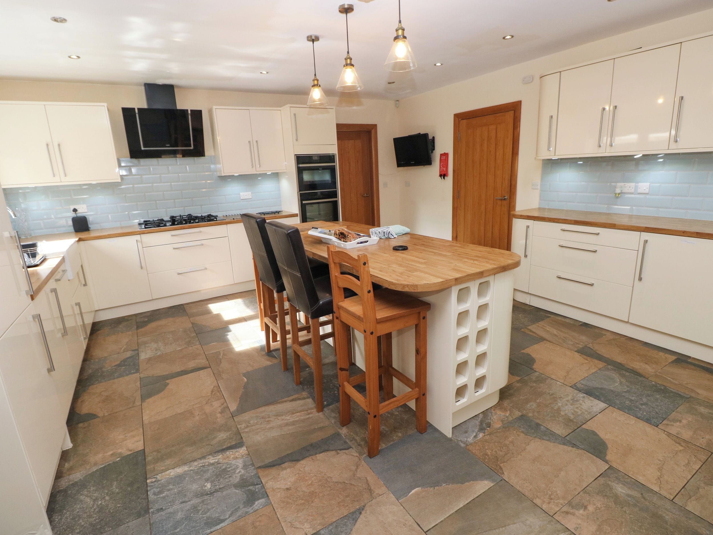A modern kitchen with white cabinets, a wooden island, and a tiled floor.