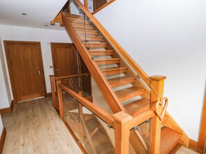 Una escalera de madera con barandillas de vidrio en una habitación con suelo y puertas de madera.