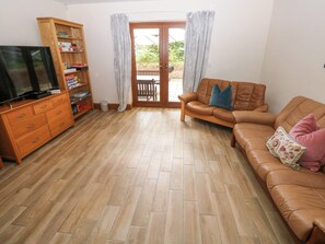 Una sala de estar con un mueble de madera, un sofá de cuero y un televisor.