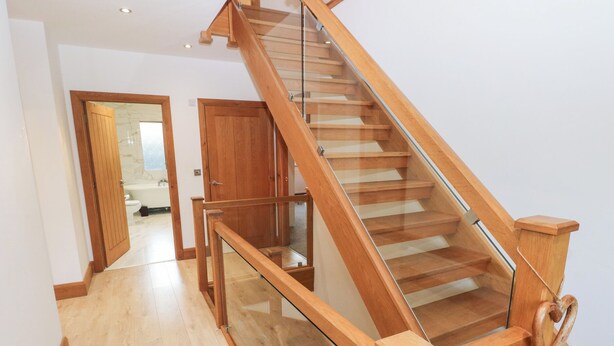 Una escalera de madera con barandillas de vidrio que sube a un piso superior.