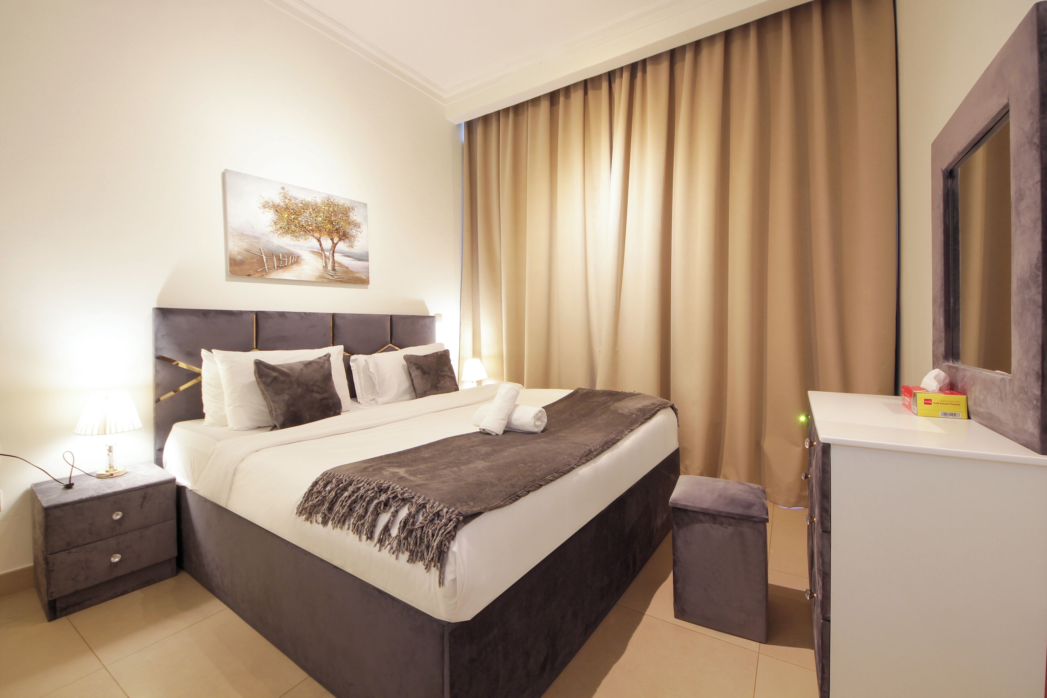 Ein modernes Hotelzimmer mit einem großen Bett, einem Nachttisch, einem Schreibtisch und einem Bild an der Wand.