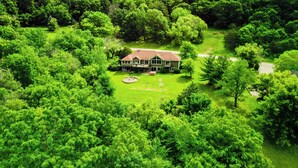 A large house surrounded by lush greenery, with a well-maintained lawn and a driveway leading to the entrance. - Grand Galena Hideaway [ Luxe Retreat w/ Hot Tub & Games ] (Galena)