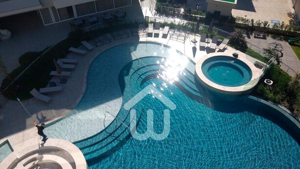 A large, circular swimming pool with a central island and a smaller pool on the right. - Sofisticação e Conforto Città Life (Florianópolis)