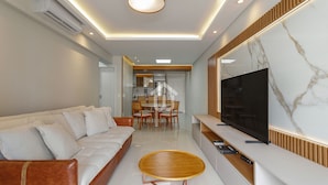 A modern living room with a sofa, a coffee table, and a TV on a wall. - Sofisticação e Conforto Città Life (Florianópolis)