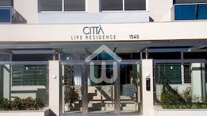 A modern building entrance with a glass door, a metal staircase, and a sign reading "CITTA LIFE RESIDENCE 1540". - Sofisticação e Conforto Città Life (Florianópolis)