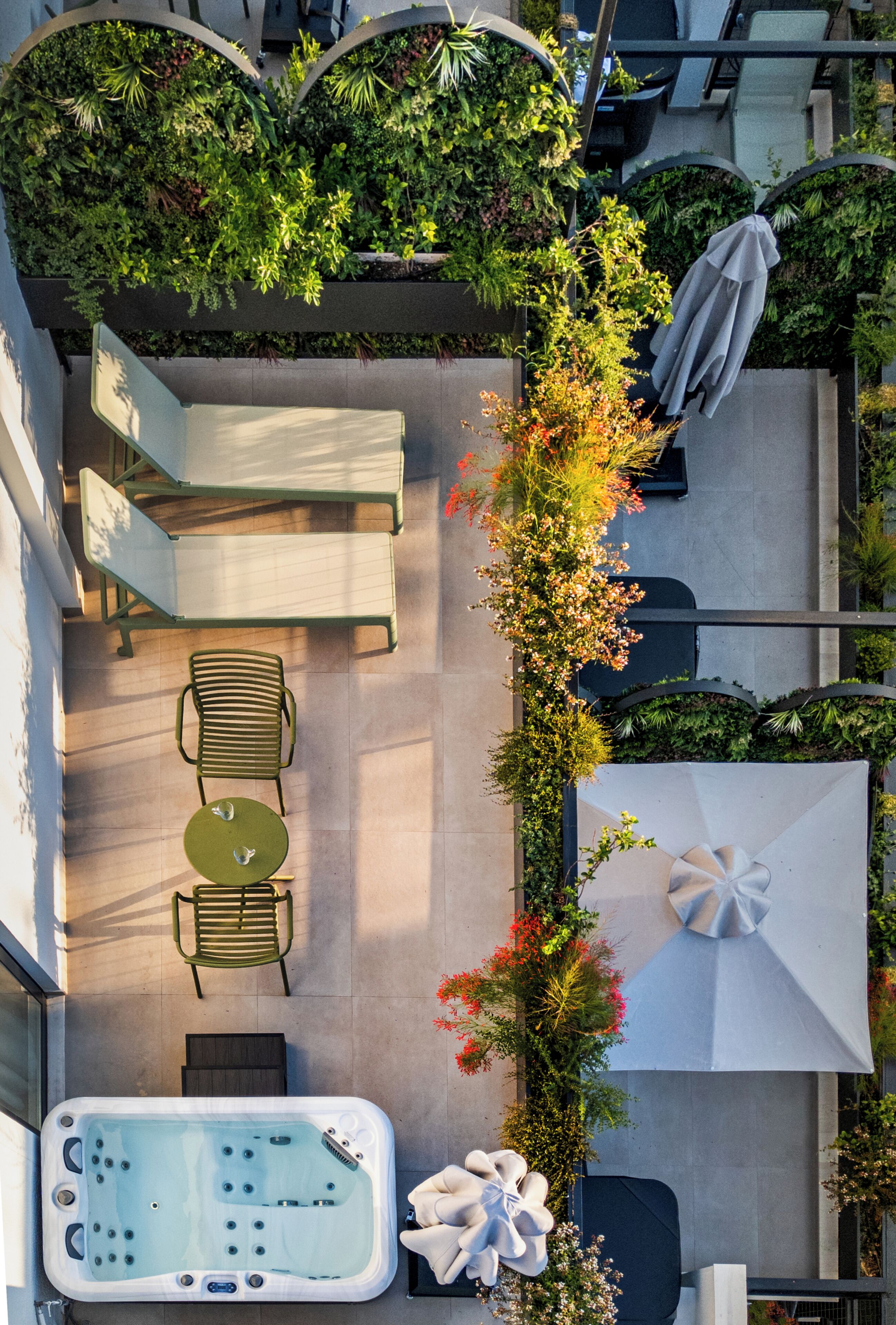 Une terrasse extérieure dotée d’un jacuzzi, d’un espace salon et d’une végétation luxuriante.