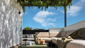 A modern outdoor seating area with a sofa, a table, and candles. - Zea Urban Living (Piraeus)