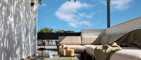 A modern outdoor seating area with a sofa, a table, and candles.