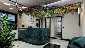 A reception desk with a green marble top, a clock, and a WC sign. - Zea Urban Living (Piraeus)