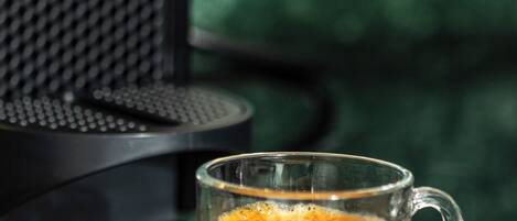 Una tassa de cafè sobre un calze, al costat d'una cafetera.